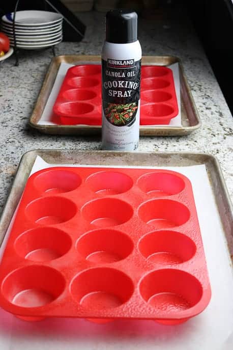 2 red silicone muffin cups on a granite counter with cooking spray from Gourmet Done Skinny