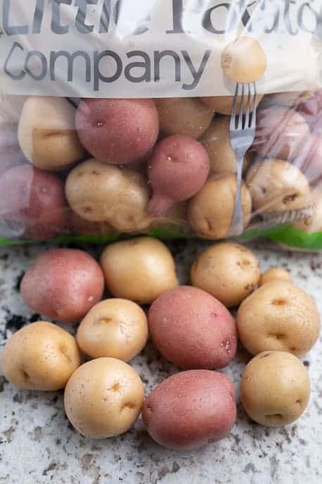 Baby potatoes in a bag and loose potatoes in front.
