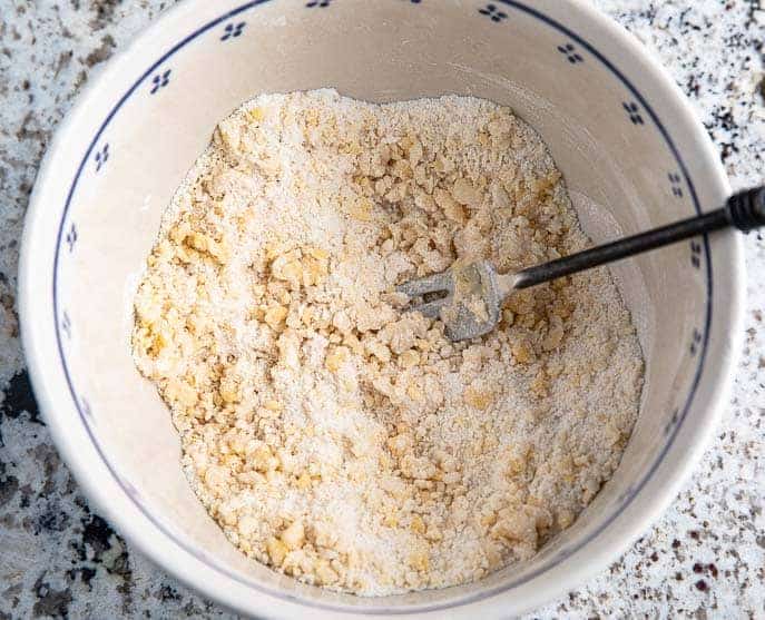 bowl with egg, flour and sugar crumbles, black fork on a granite counter top