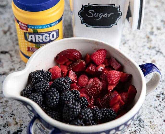 bowl with blackberries, strawberries; cornstarch and sugar in the background on a granite countertop