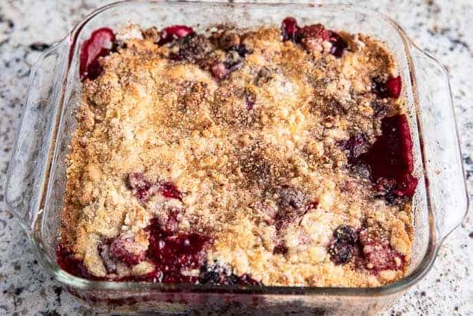 fresh homemade berry cobbler in a square glass dish on a granite counter top