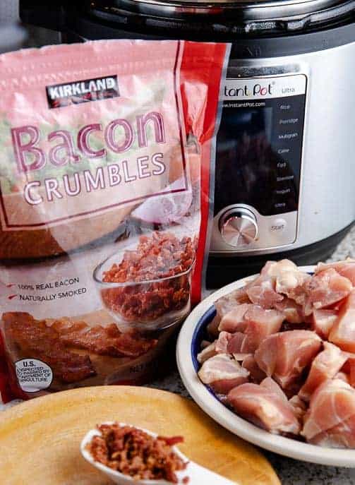 bacon crumbles bag, raw chicken in a bowl, bacon crumbles in a tablespoon with Instant Pot in the background
