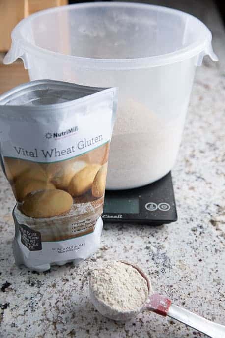 bucket on a scale, vital wheat gluten in a measuring cup with vital wheat gluten package