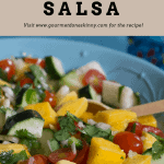 Colorful Mango Salsa in a blue bowl with wooden spoon