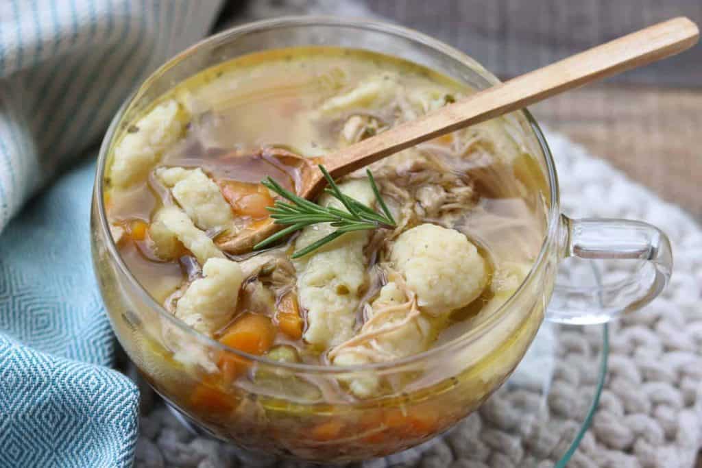 Healthy Soup Recipes: Delicious homemade chicken noodle soup in a glass cup with a wooden spoon from Gourmet Done Skinny