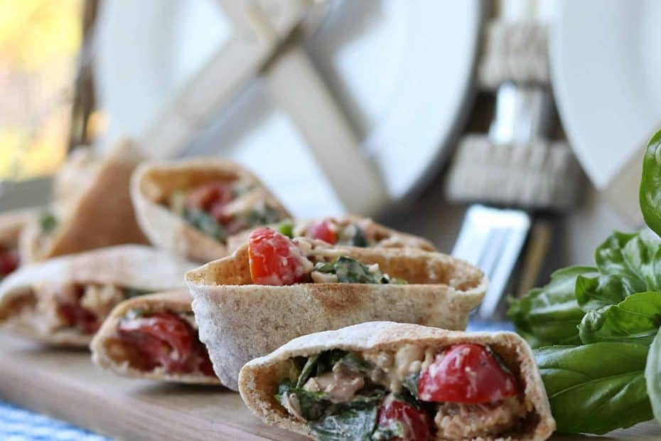 Mini Chicken Basil Parmesan Pitas on a wooden board with basil and picnic basket