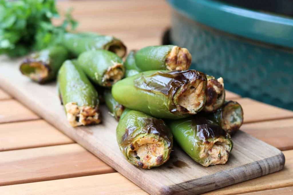 Healthy Jalapeño Poppers grilled on a wooden board next to the Big Green Egg