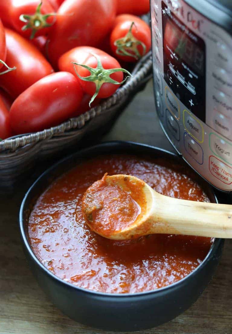 tomato sauce in black bowl with wooden spoon