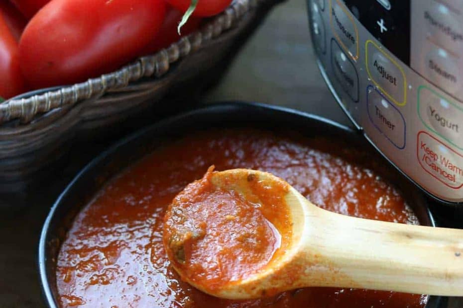 Instant Pot Homemade Tomato Sauce in a black bowl with Instant Pot and basket of tomatoes in background