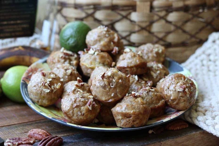 Jamaican Banana Bread Muffins on a plate with basket, lime, and pecans
