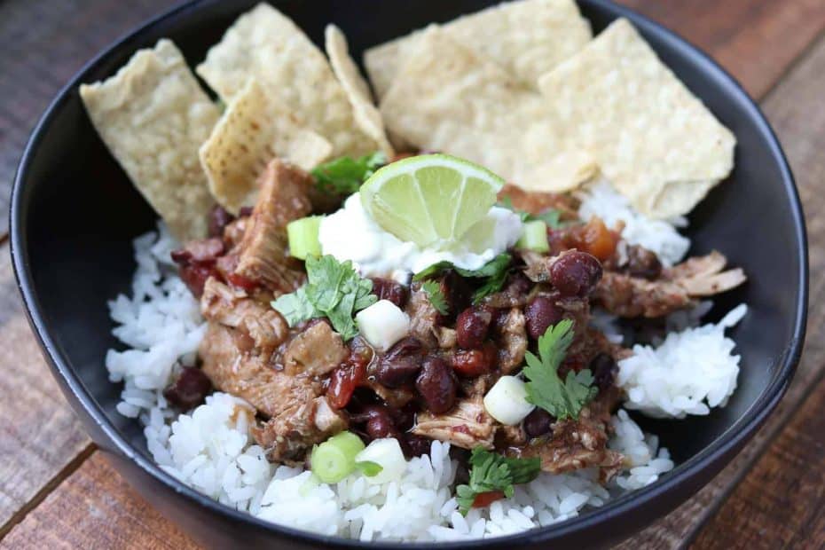 Quick and Easy Healthy Cilantro Pork Pot in a black bowl with rice, lime and tortilla chips