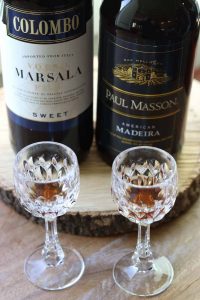 Madeira and Masala wine bottles with wine glasses on a wooden board from Gourmet Done Skinny