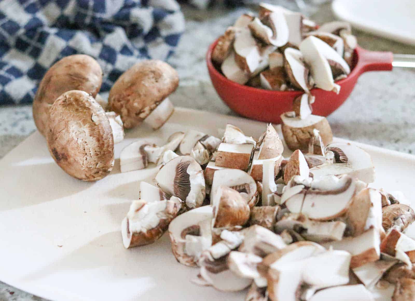 Chopped mushrooms on a white cutting board from Gourmet Done Skinny