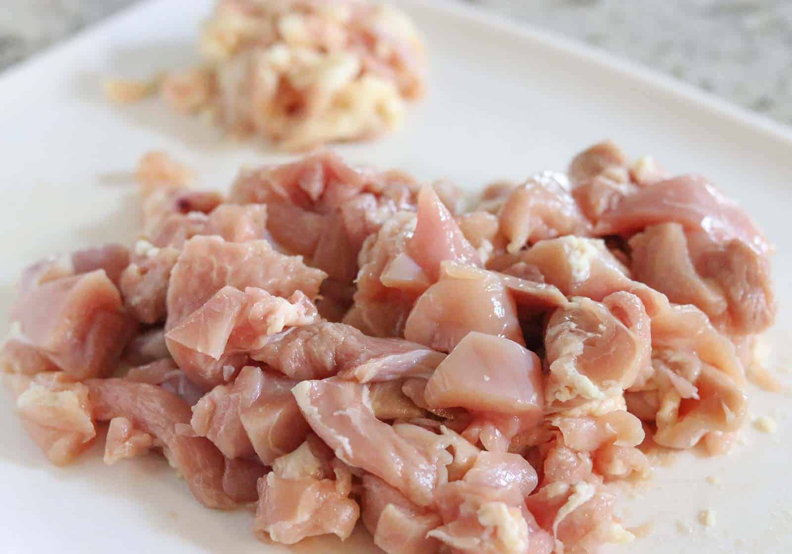 Making Chicken Madeira - Raw chicken with pieces of fat cut off on a white cutting board from Gourmet Done Skinny