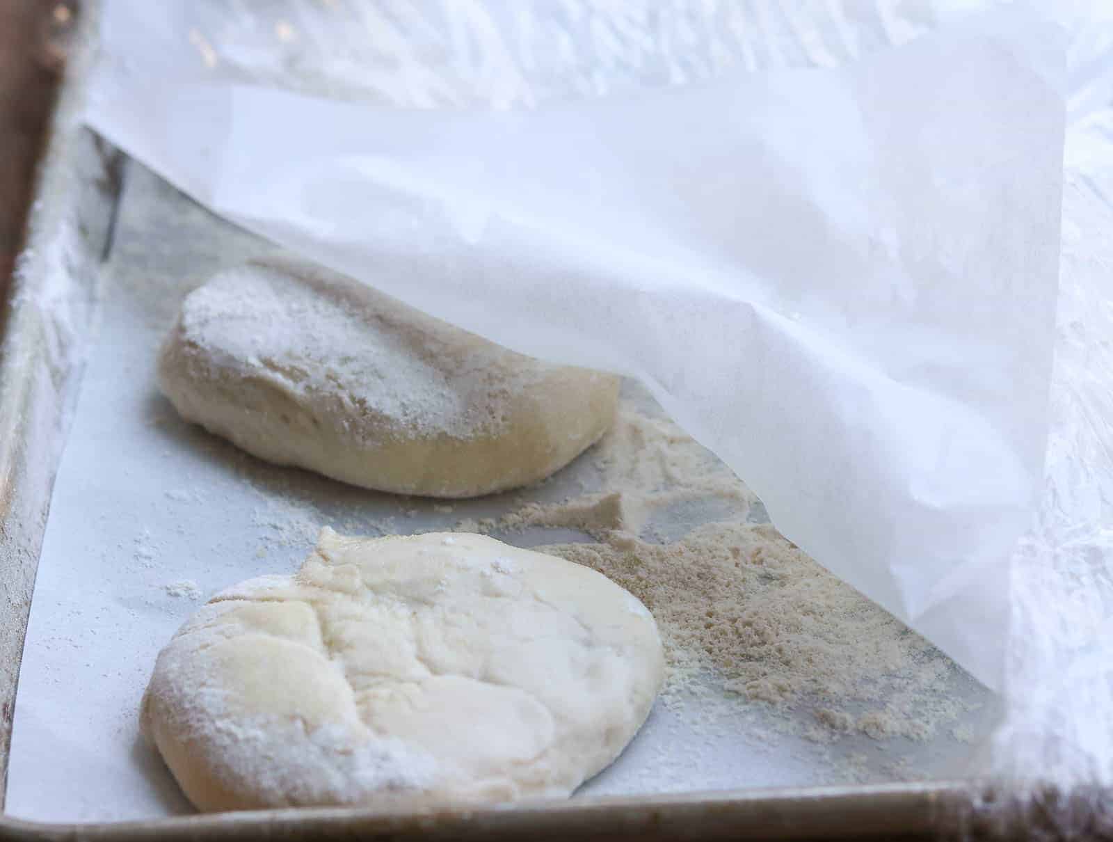 baking sheet with partially covered pizza dough and parchment paper from Gourmet Done Skinny