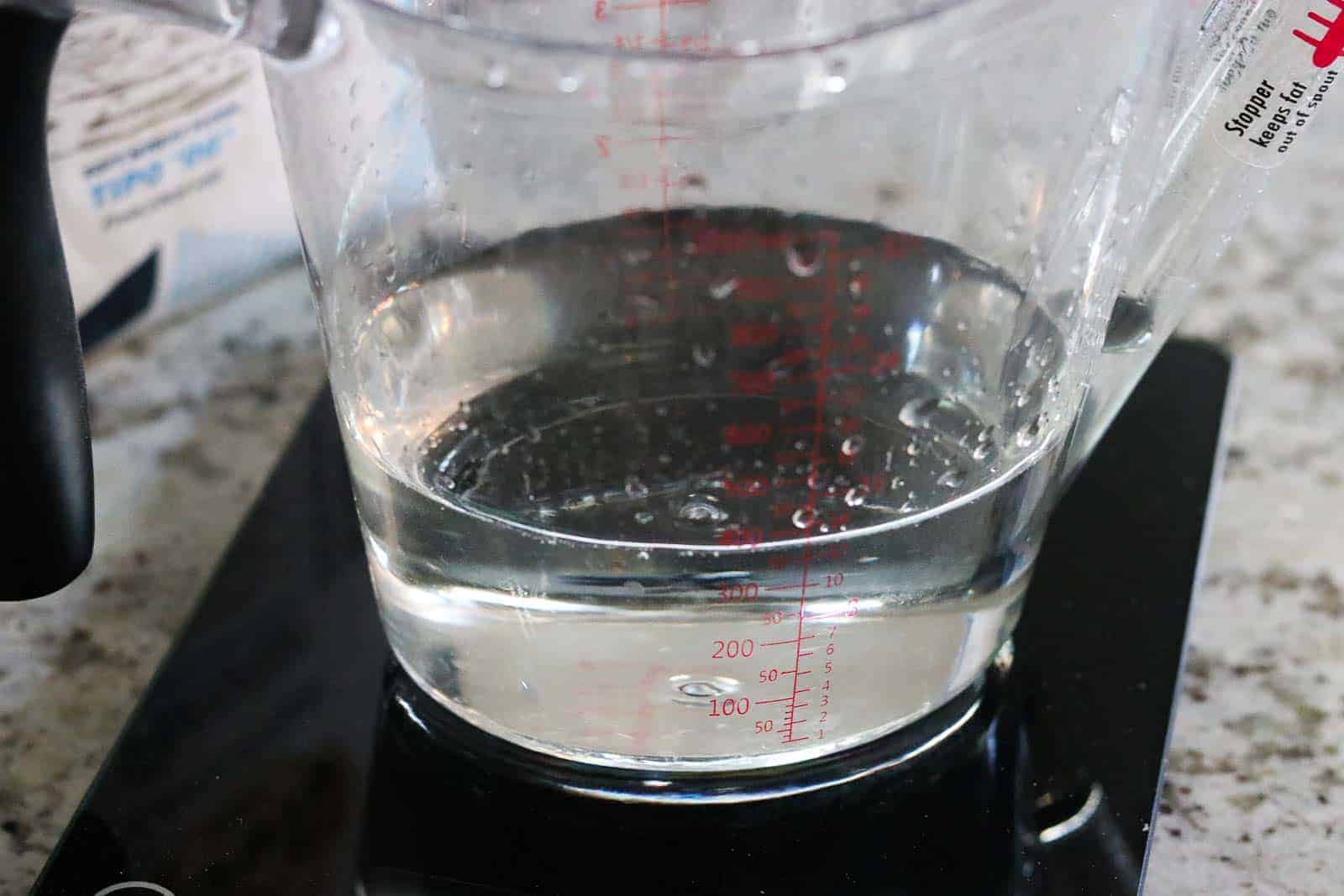 clear liquid measuring cup with water on a kitchen scale