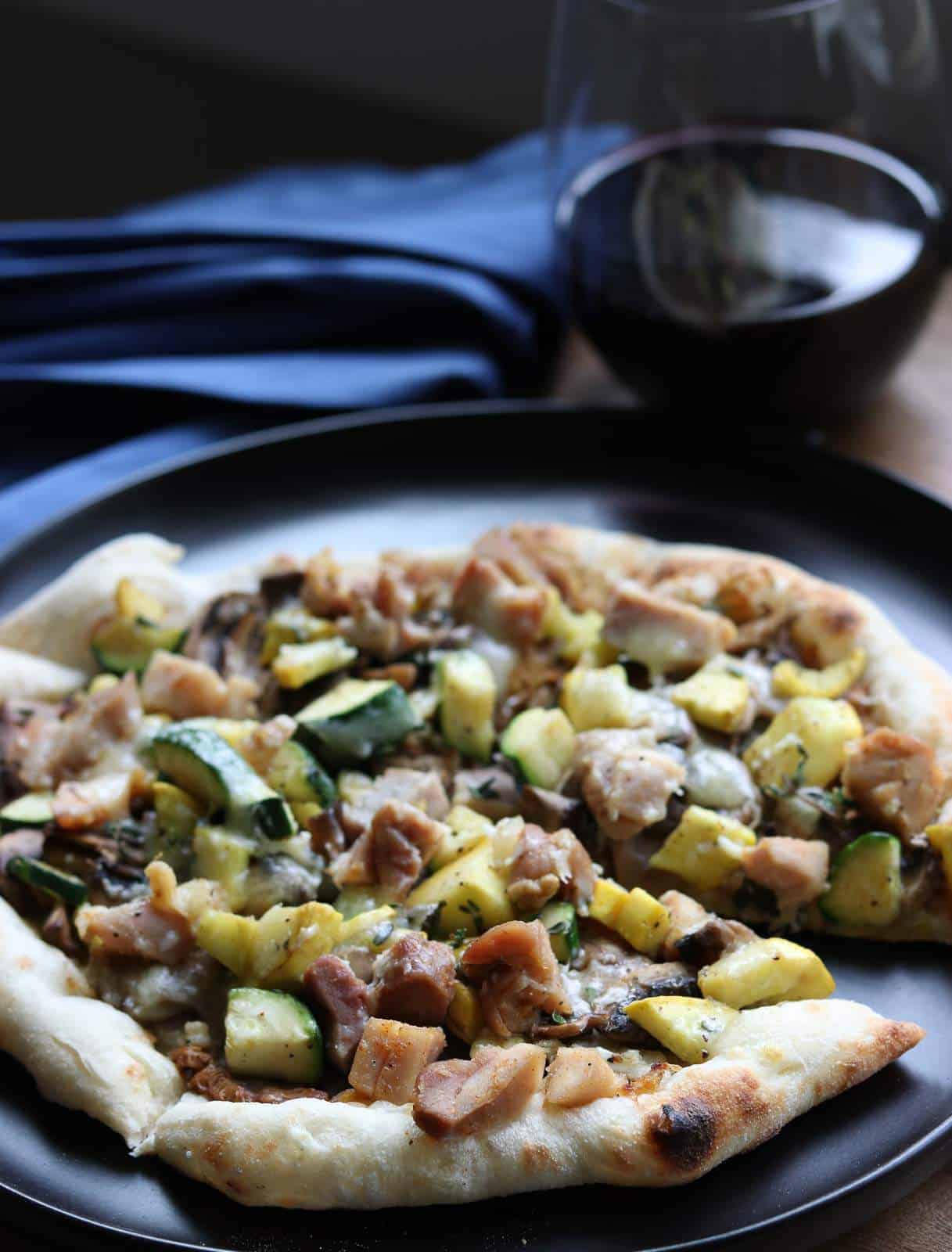 Wild Mushroom Pizza with Chicken, Zucchini and Truffle Oil on a black plate
