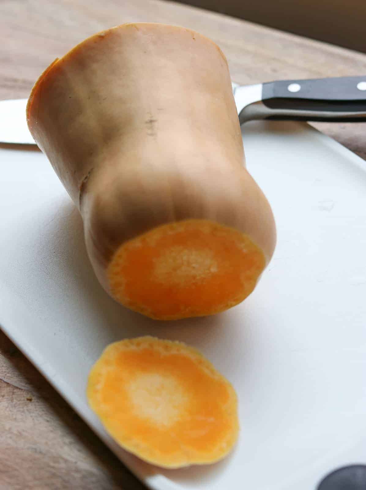 Butternut squash on a white cutting board with top and bottom cut off from Gourmet Done Skinny