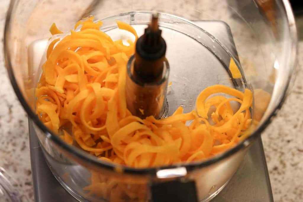 Magimix food processor with spiralized butternut squash in the work bowl on a wooden board by Gourmet Done Skinny