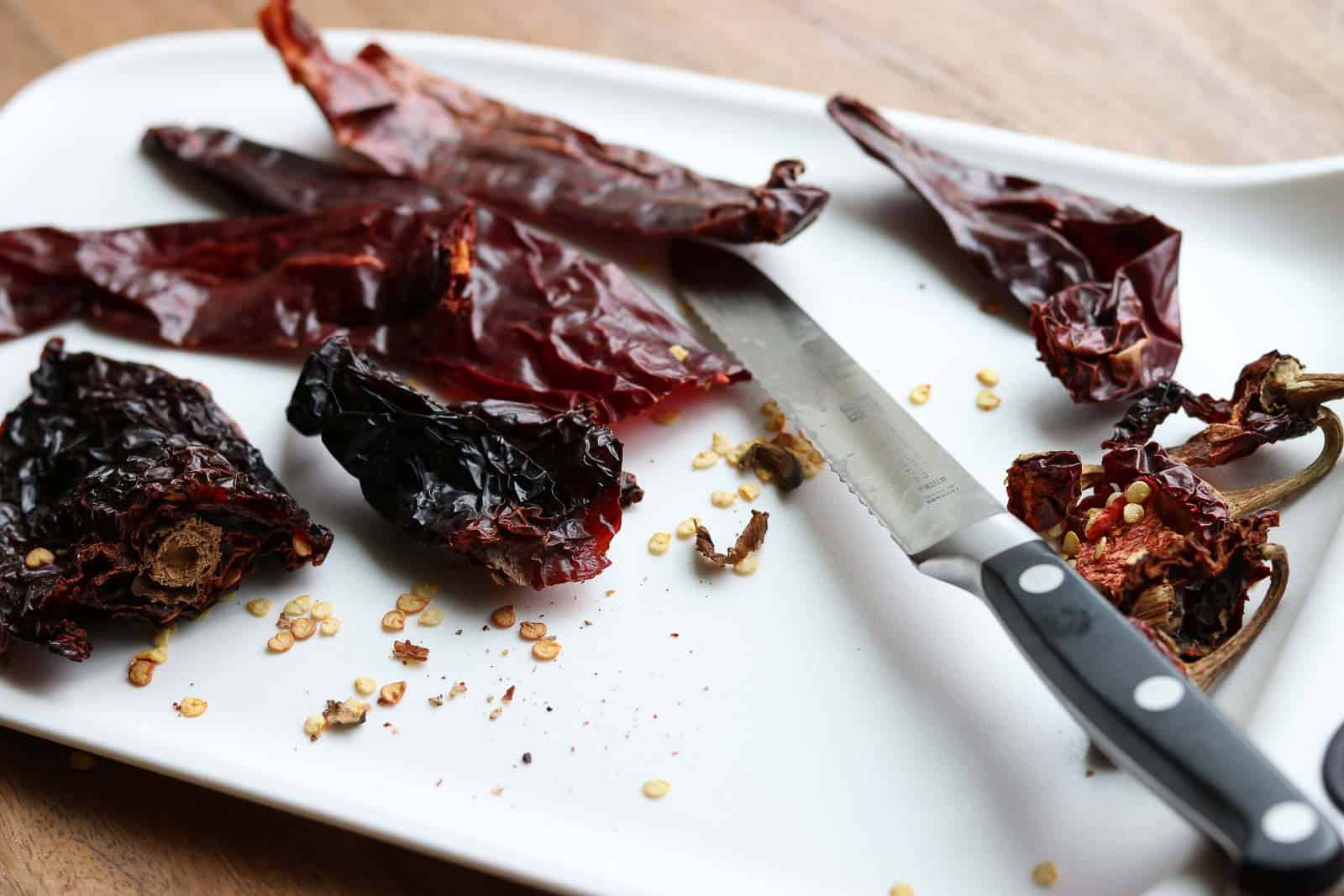 Dried chiles with stems cut off on a white cutting board from Gourmet Done Skinny