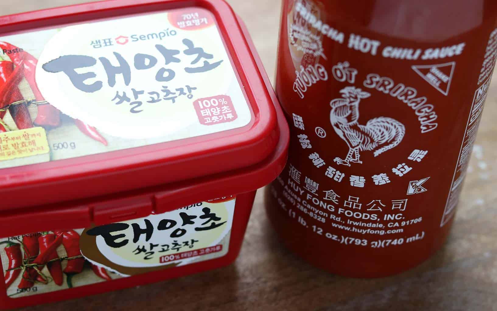 Gochujang and Sriracha sauce in original containers on a wooden board from Gourmet Done Skinny