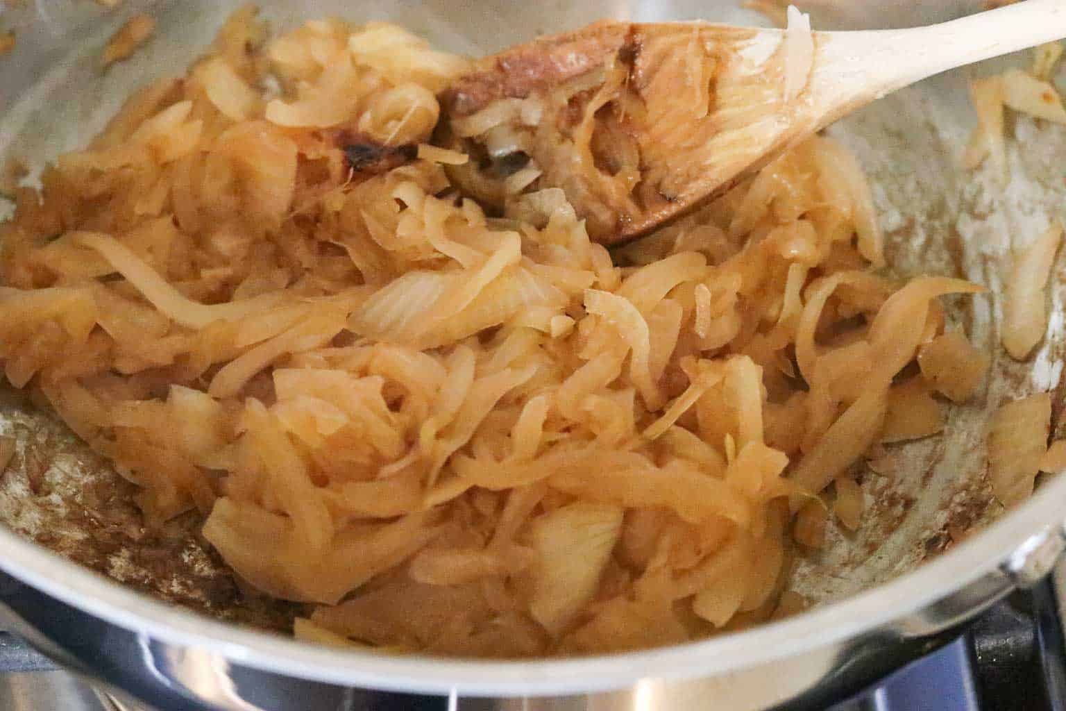 Caramelized onions in a metal pan with wooden spoon from Gourmet Done Skinny
