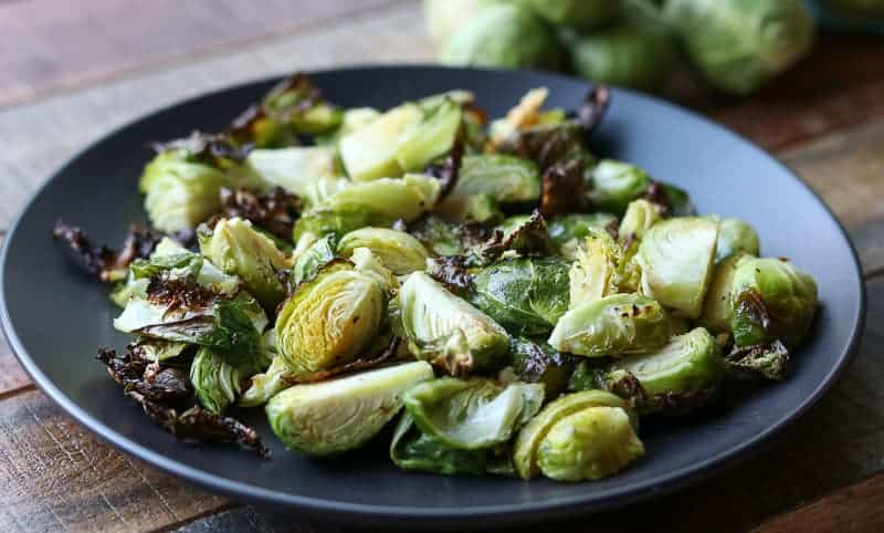 Air fried brussels sprouts on black plate on a wooden board from Gourmet Done Skinny