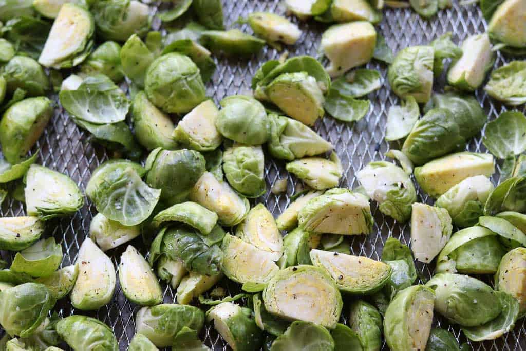 Brussels sprouts ready to be air fried in an air fryer basket from Gourmet Done Skinny