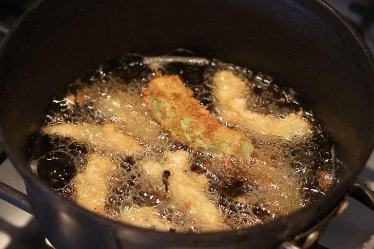 Skillet on stove with oil containing deep fried avocados from Gourmet Done Skinny