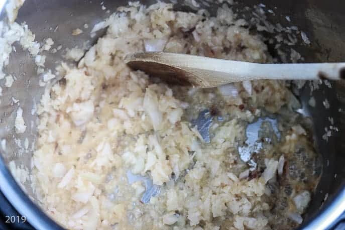 Instant Pot liner with onions, garlic and a wooden spoon from Gourmet Done Skinny
