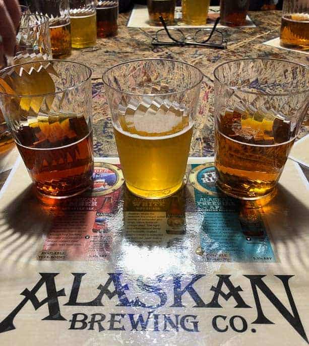 3 beers from the Alaskan Brewing company on a placemat with descriptions of the beers