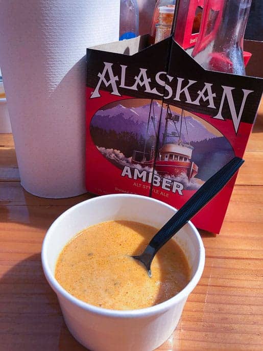 Delicious, decadent crab bisque from Tracy's King Crab Shack in a white styrofoam bowl on a wooden table