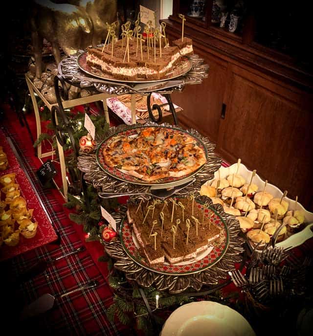 It is so hard to stick to a diet, and not cheat especially during the holidays. Holiday table with an abundant assortment of various plates of food. Sandwiches, pizza, appetizers from Gourmet Done Skinny