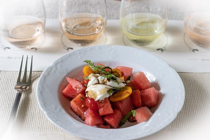 Summer Watermelon Tomato Salad with Burrata, Mint and Basil in a white plate with 4 wine pairing from Gourmet Done Skinny