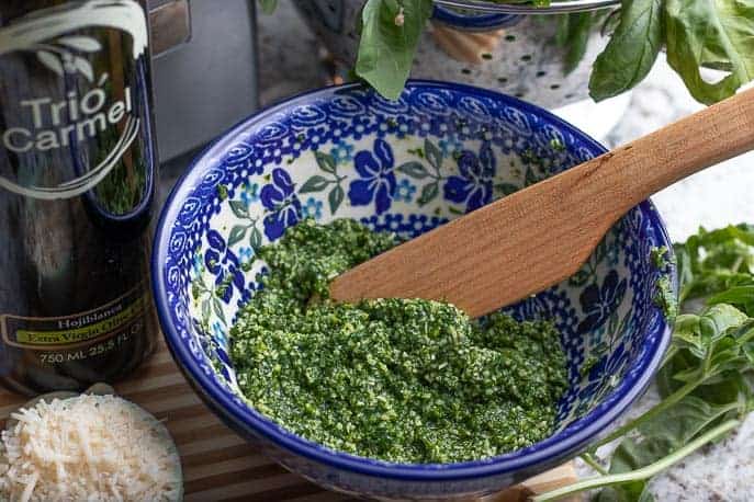 Homemade basil pesto in a Polish pottery bowl with a wooden spoon from Gourmet Done Skinny