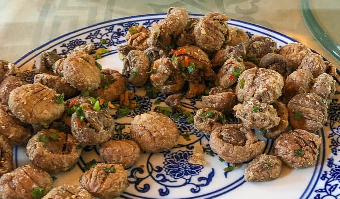 Fried mushrooms on a blue and white plate at Huajia Yiyuan
