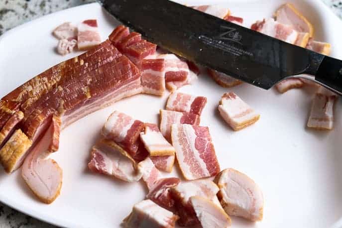 Cut bacon on a white cutting board with a chef knife from Gourmet Done Skinny