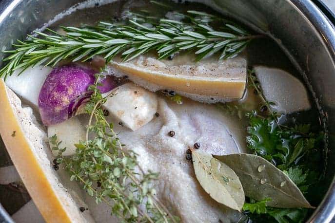 Whole chicken, parmesan rinds, rosemary, bay leaves, parsley in the Instant Pot from Gourmet Done Skinny