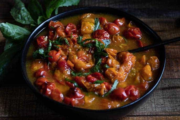 Roasted tomato sauce in a black bowl, not blended but whole cherry tomatoes with basil on a wooden board from Gourmet Done Skinny