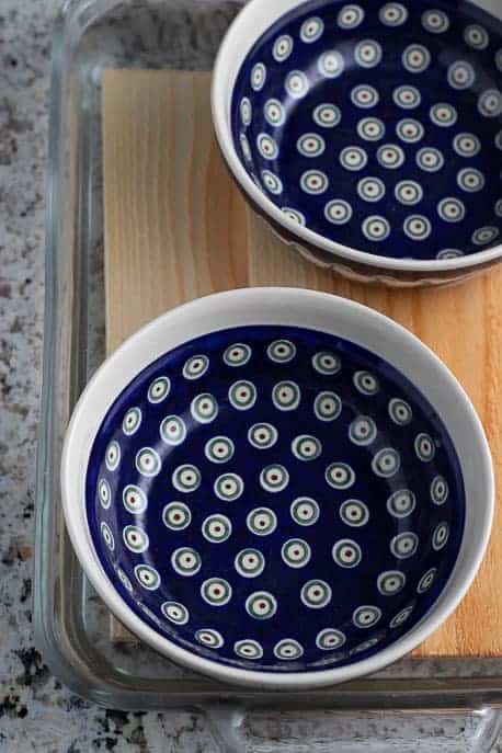 Cedar planks soaking in a glass dish with Polish pottery bowls to hold the planks down from Gourmet Done Skinny