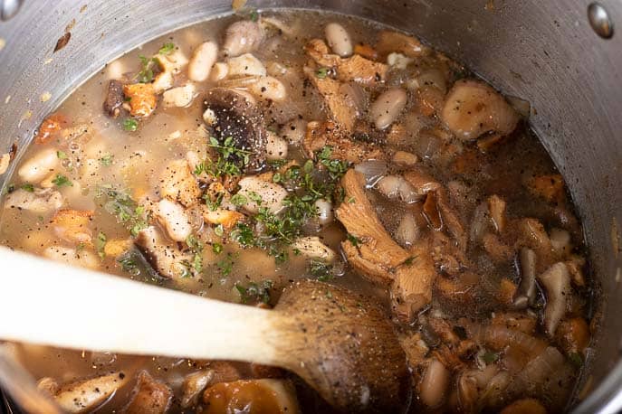 Mushrooms, beans, pepper, thyme and wooden spoon in a pot from Gourmet Done Skinny