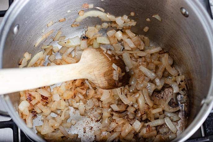 Onions browning in a pot with a wooden spoon from Gourmet Done Skinny