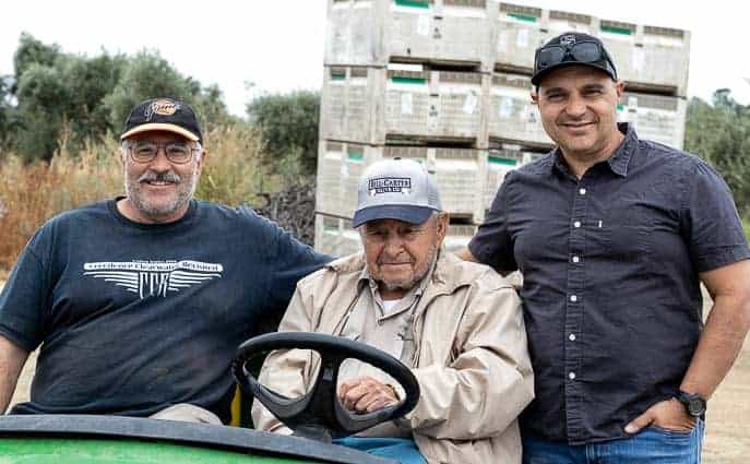 Joe, Marciano, Ed Curiel in front of bins of olives from Gourmet Done Skinny