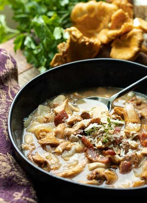 Healthy Mushroom soup in a black bowl with spoon and mushrooms and napkin from Gourmet Done Skinny