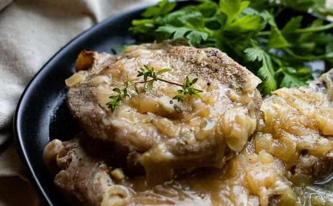 Healthy Instant Pot Pork Chops on a black plate with parsley from Gourmet Done Skinny