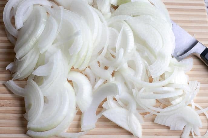 White onions on a cutting board with knife from Gourmet Done Skinny