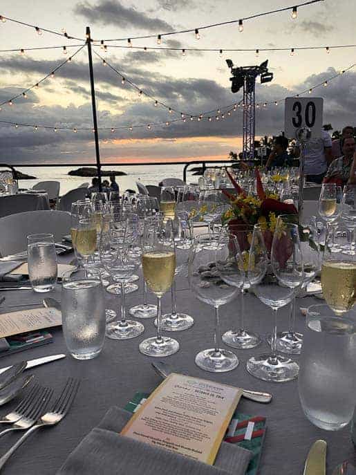 Wine glasses, tableware on a table on the beach with the sunset