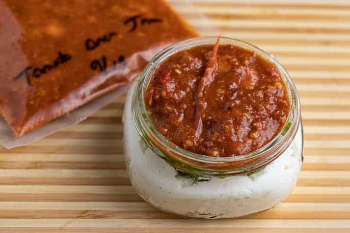 Tomato bacon jam in a package on a cutting board with tomato bacon ricotta jam in a jar