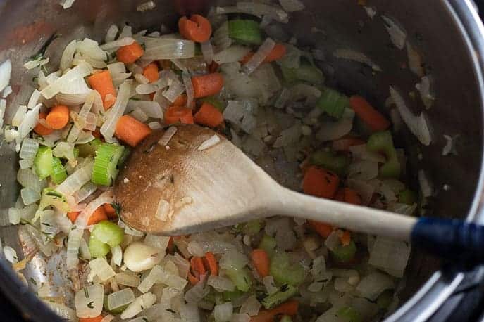 Onions, carrots, celery and herbs cooking in Instant Pot