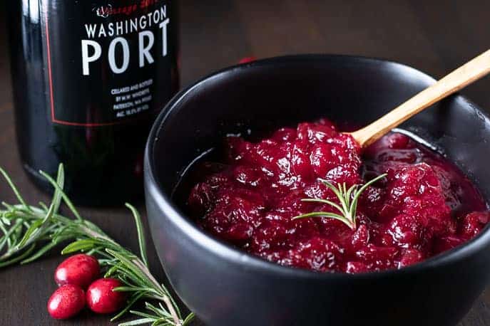 cranberry sauce in a black bowl with a bottle of port on the side